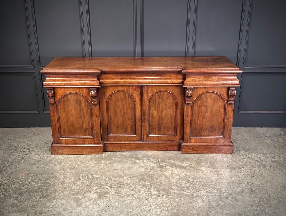 A Victorian mahogany four-door breakfront sideboard featuring arched panel doors, carved support brackets, and a long flat top surface. View IV