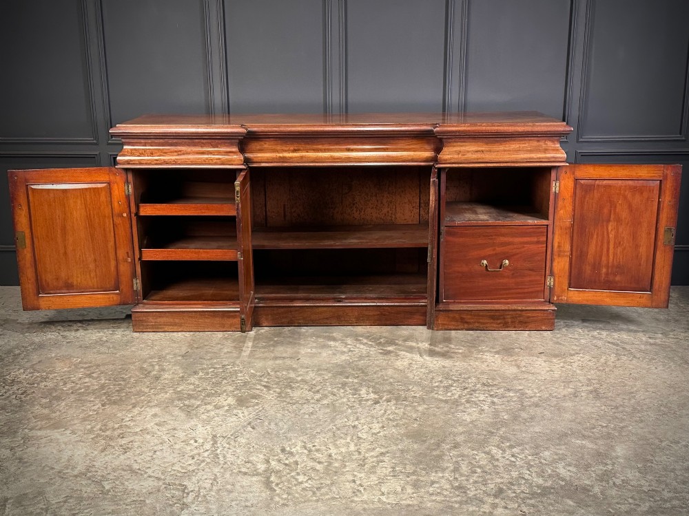A Victorian mahogany four-door breakfront sideboard featuring arched panel doors, carved support brackets, and a long flat top surface. View V