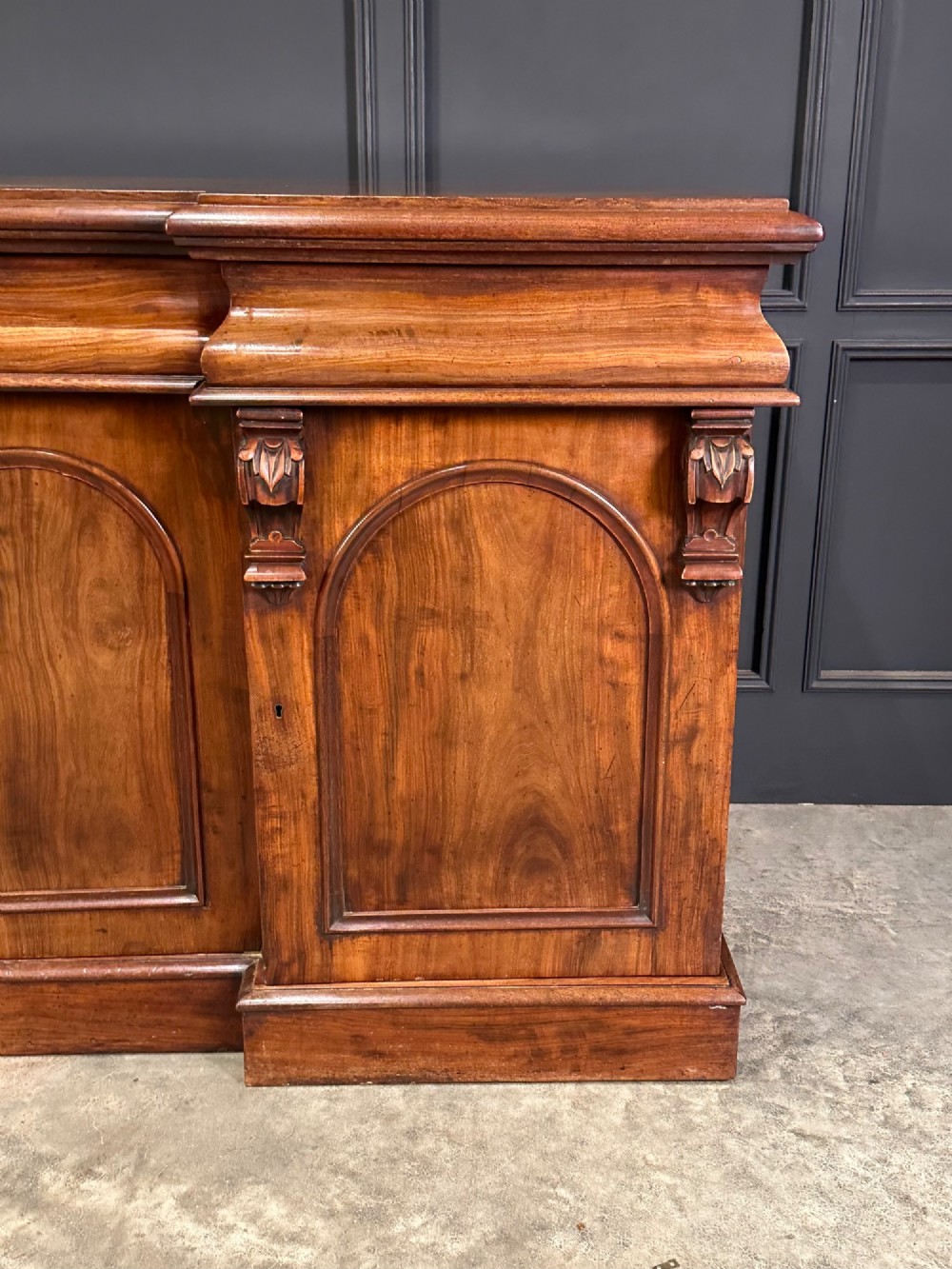 A Victorian mahogany four-door breakfront sideboard featuring arched panel doors, carved support brackets, and a long flat top surface. View VII