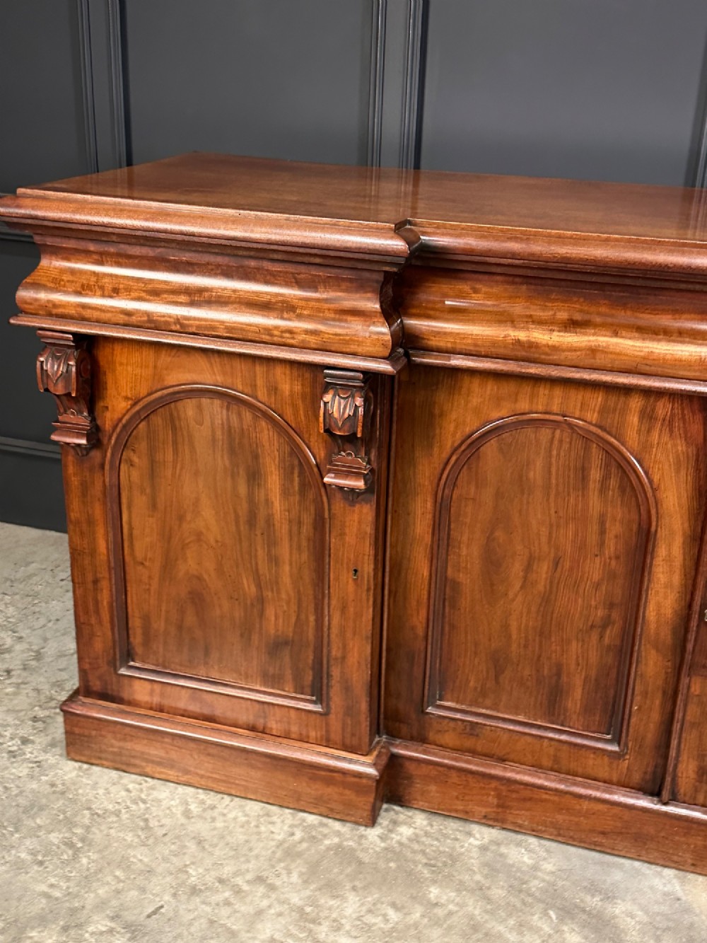 A Victorian mahogany four-door breakfront sideboard featuring arched panel doors, carved support brackets, and a long flat top surface. View VIII