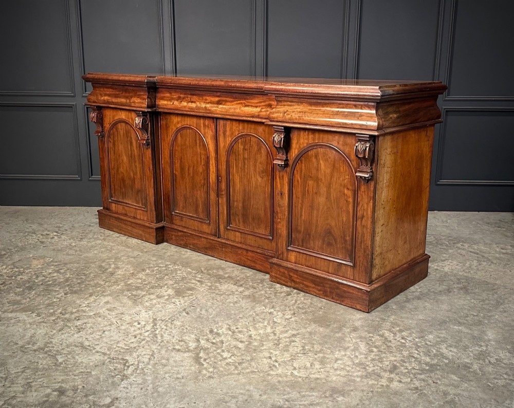 A Victorian mahogany four-door breakfront sideboard featuring arched panel doors, carved support brackets, and a long flat top surface. View XI