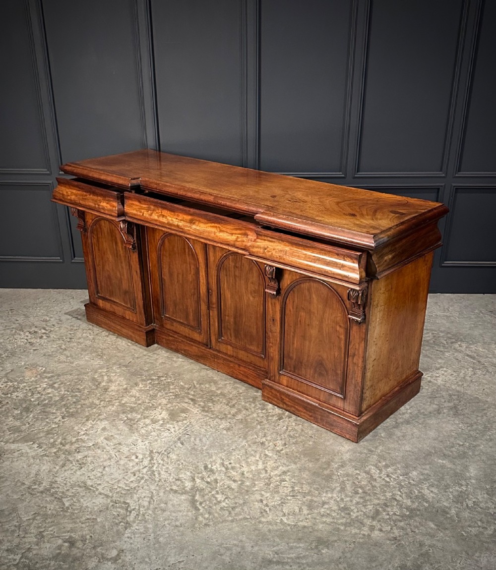 A Victorian mahogany four-door breakfront sideboard featuring arched panel doors, carved support brackets, and a long flat top surface. View XII