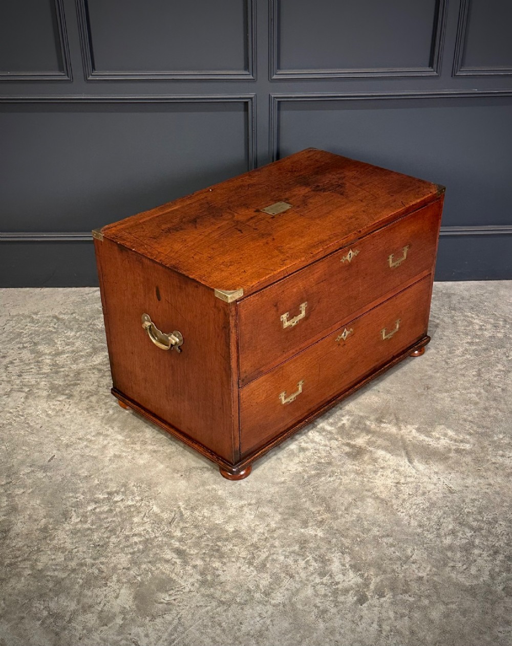 A pair of low two-drawer Regency teak military campaign chests featuring recessed brass handles, flush corner brackets, and turnip feet. View IV