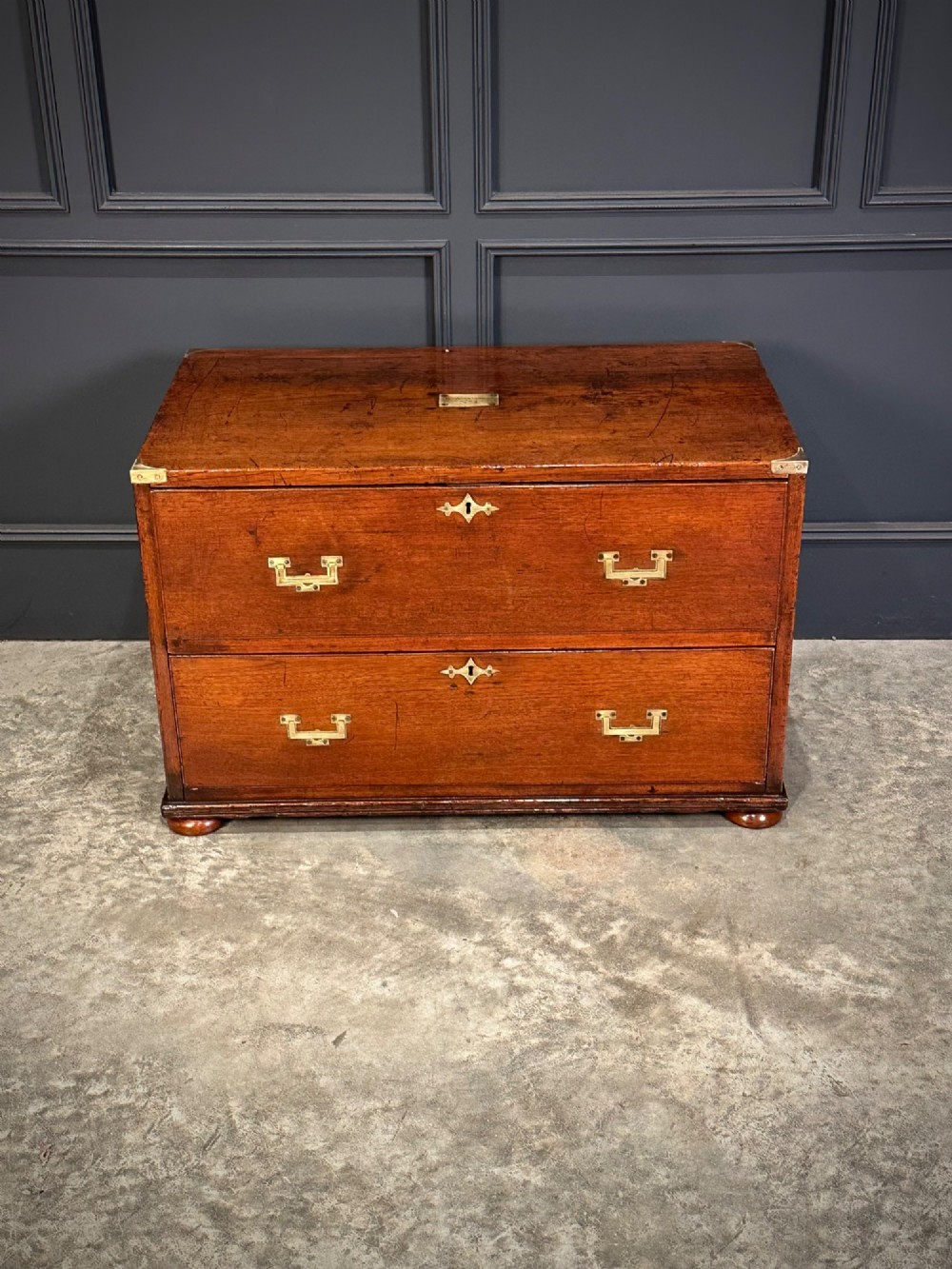 A pair of low two-drawer Regency teak military campaign chests featuring recessed brass handles, flush corner brackets, and turnip feet. View VI