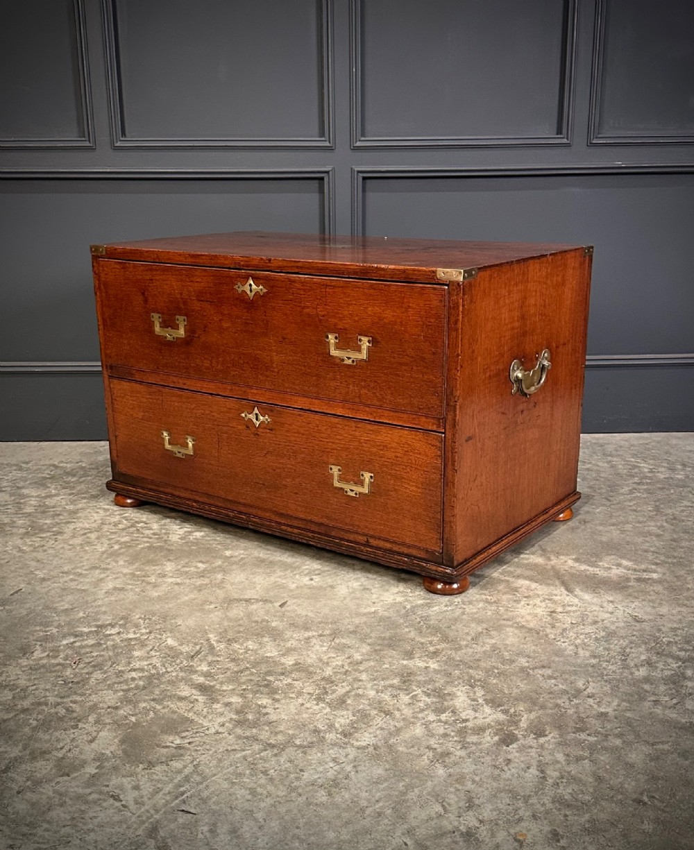 A pair of low two-drawer Regency teak military campaign chests featuring recessed brass handles, flush corner brackets, and turnip feet. View VII