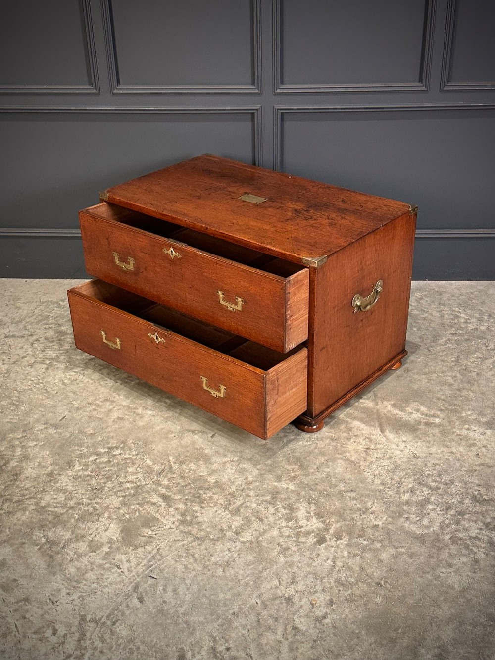 A pair of low two-drawer Regency teak military campaign chests featuring recessed brass handles, flush corner brackets, and turnip feet. View VIII