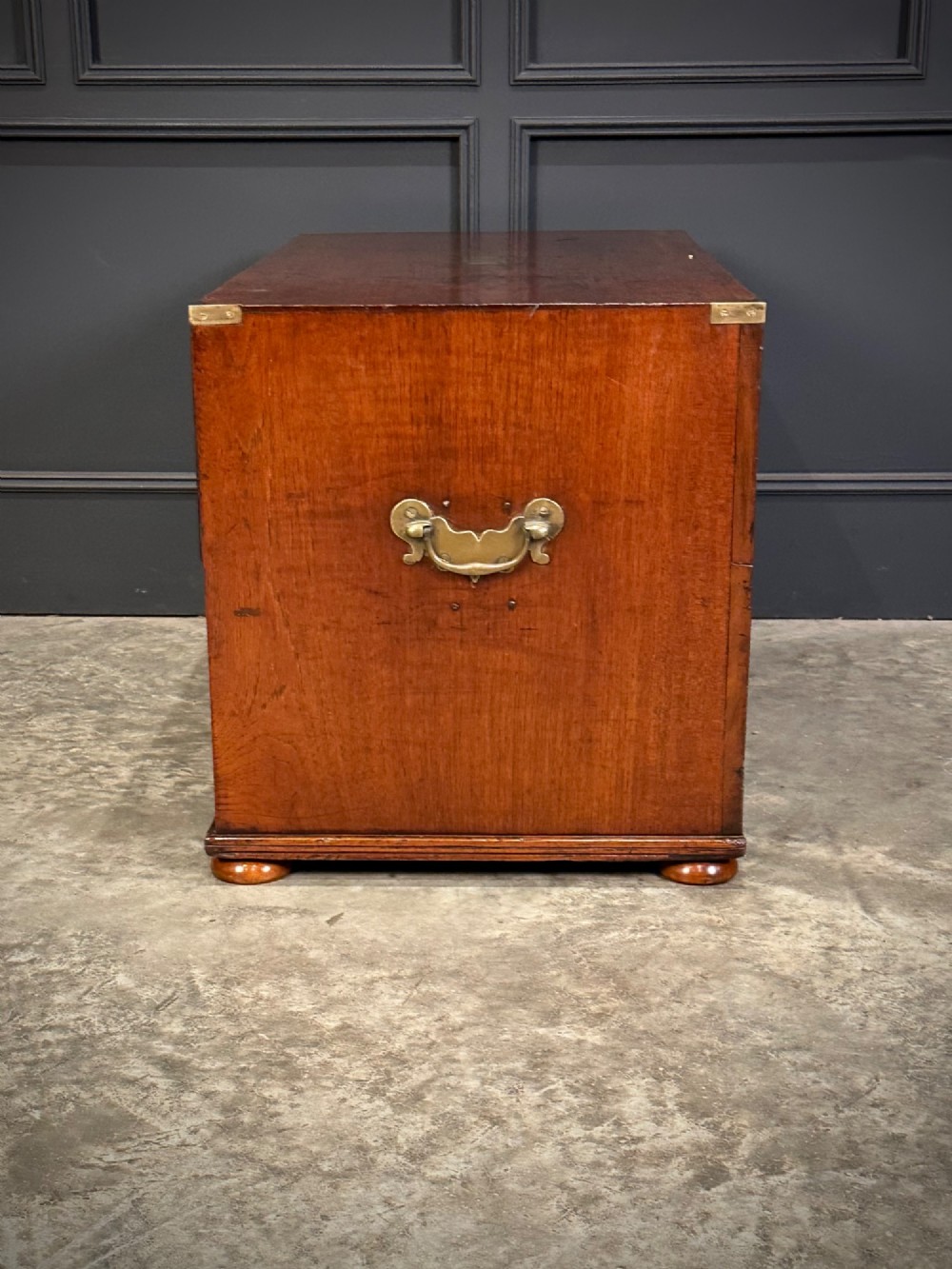 A pair of low two-drawer Regency teak military campaign chests featuring recessed brass handles, flush corner brackets, and turnip feet. View IX