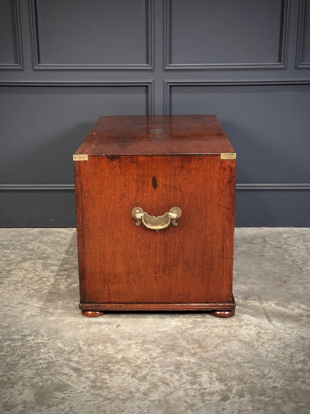 A pair of low two-drawer Regency teak military campaign chests featuring recessed brass handles, flush corner brackets, and turnip feet. View XI