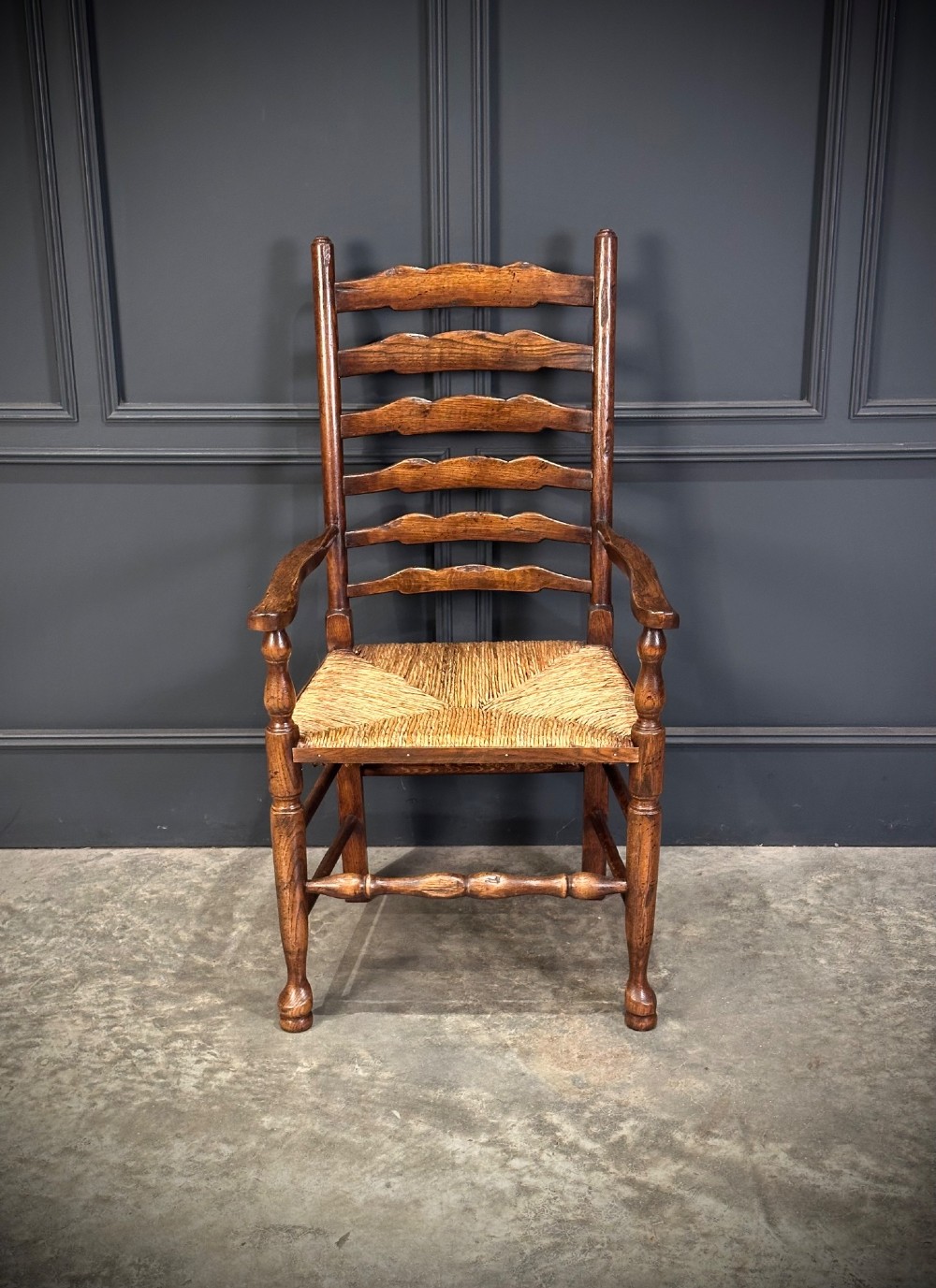 A set of eight dark oak ladder back dining chairs featuring woven rush seats, shaped back slats, and turned front legs. View IX