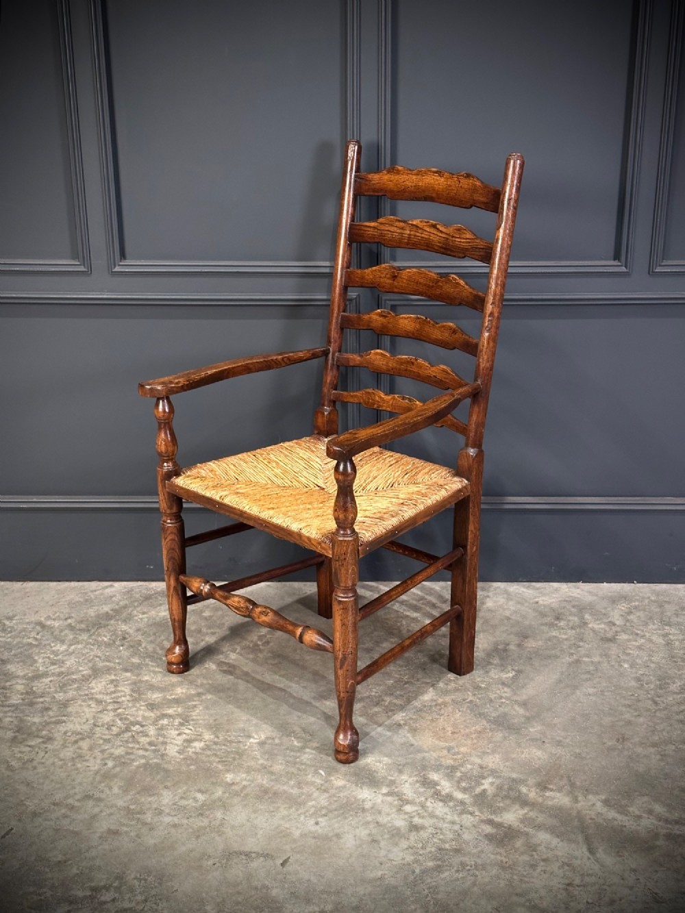 A set of eight dark oak ladder back dining chairs featuring woven rush seats, shaped back slats, and turned front legs. View X