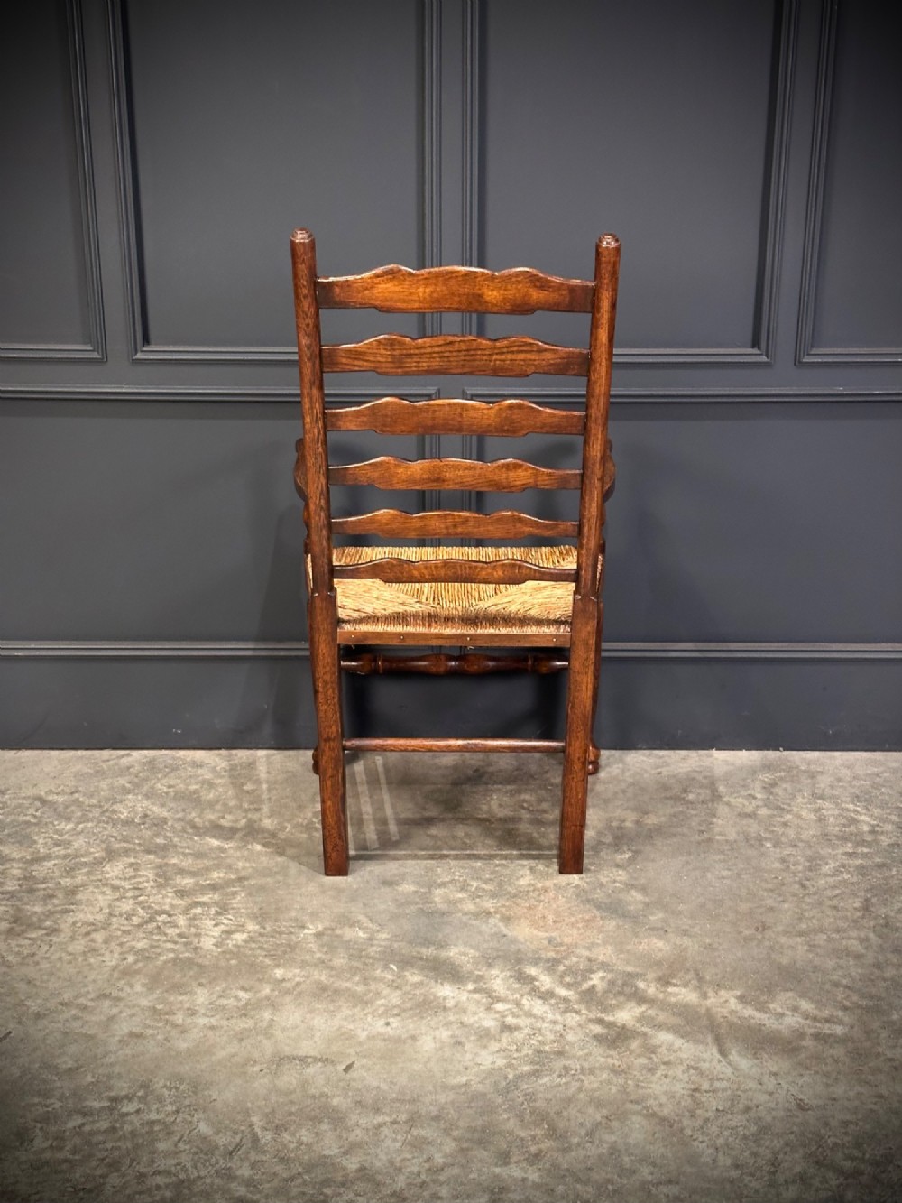 A set of eight dark oak ladder back dining chairs featuring woven rush seats, shaped back slats, and turned front legs. View XII
