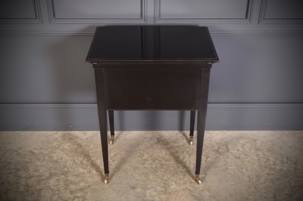 An ebonised wooden mechanical drinks table featuring opening top leaves that elevate a tray set with clear glassware, resting on tapered legs with brass castors. View XIII