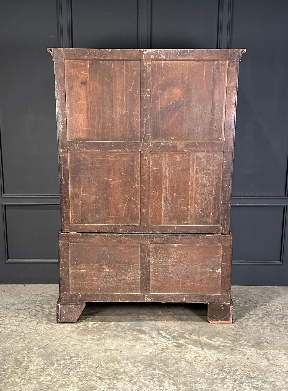 An antique Georgian mahogany gentlemans wardrobe featuring panelled upper cupboard doors above five lower drawers with brass swan-neck handles, resting on bracket feet. View VI