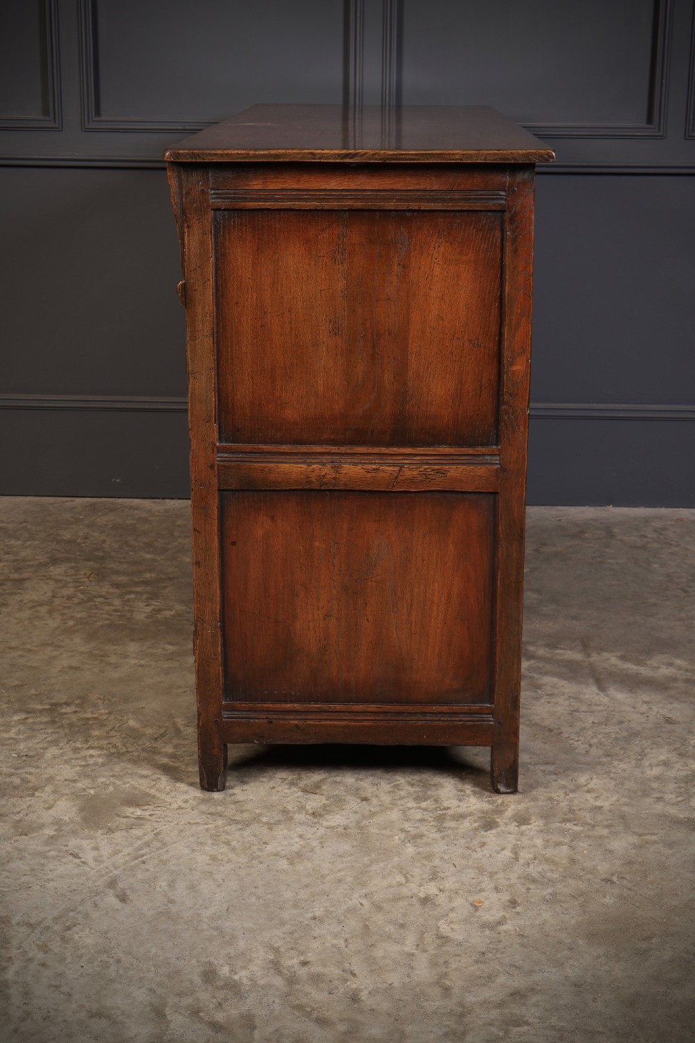 A solid oak sideboard featuring three upper drawers over four cupboard doors with carved roundhead arches and turned wooden handles. View XI