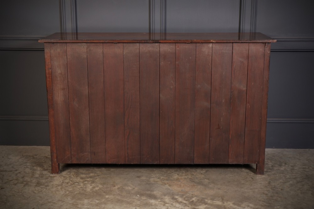 A solid oak sideboard featuring three upper drawers over four cupboard doors with carved roundhead arches and turned wooden handles. View XII