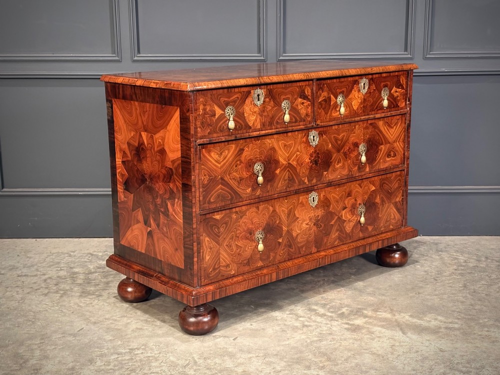 A seventeenth-century kingwood chest of drawers featuring geometric oyster veneering, brass teardrop handles, and turned bun feet. View II