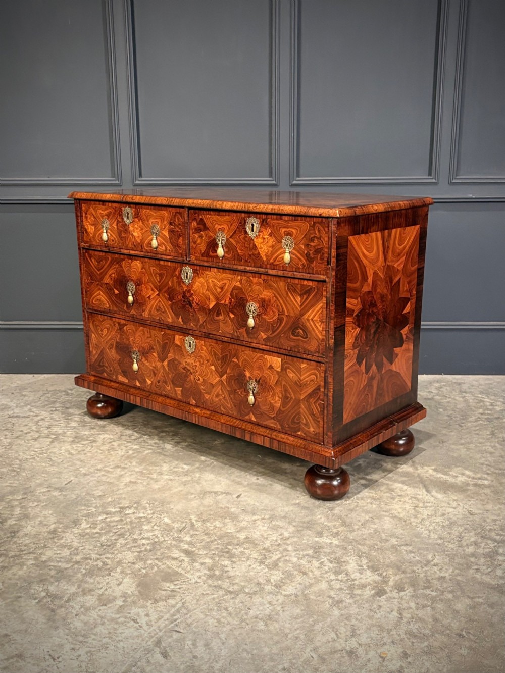 A seventeenth-century kingwood chest of drawers featuring geometric oyster veneering, brass teardrop handles, and turned bun feet. View VI