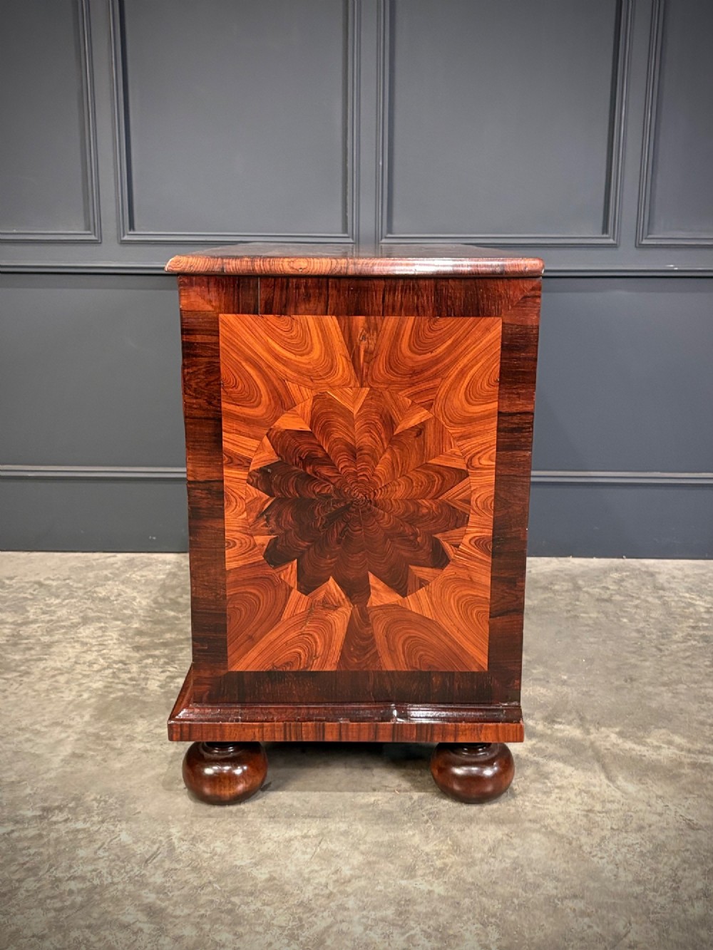 A seventeenth-century kingwood chest of drawers featuring geometric oyster veneering, brass teardrop handles, and turned bun feet. View X