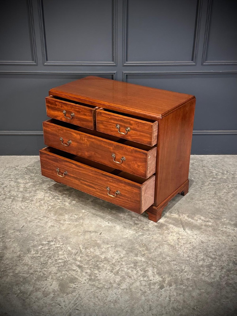 A small mahogany chest of drawers featuring two short over two long drawers with brass swan-neck handles and bracket feet. View VI