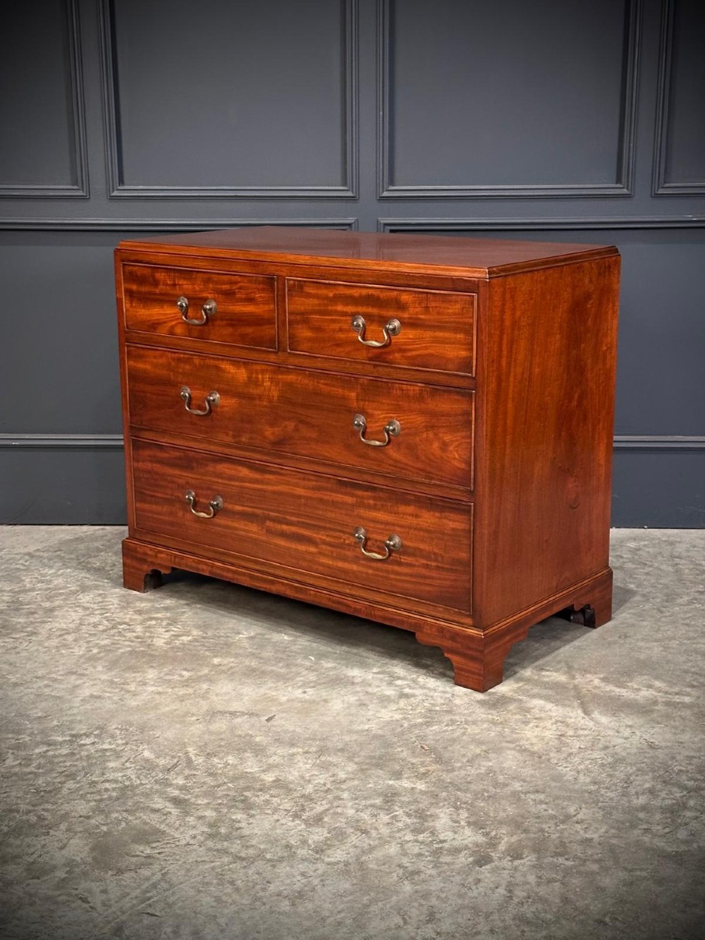 A small mahogany chest of drawers featuring two short over two long drawers with brass swan-neck handles and bracket feet. View VII
