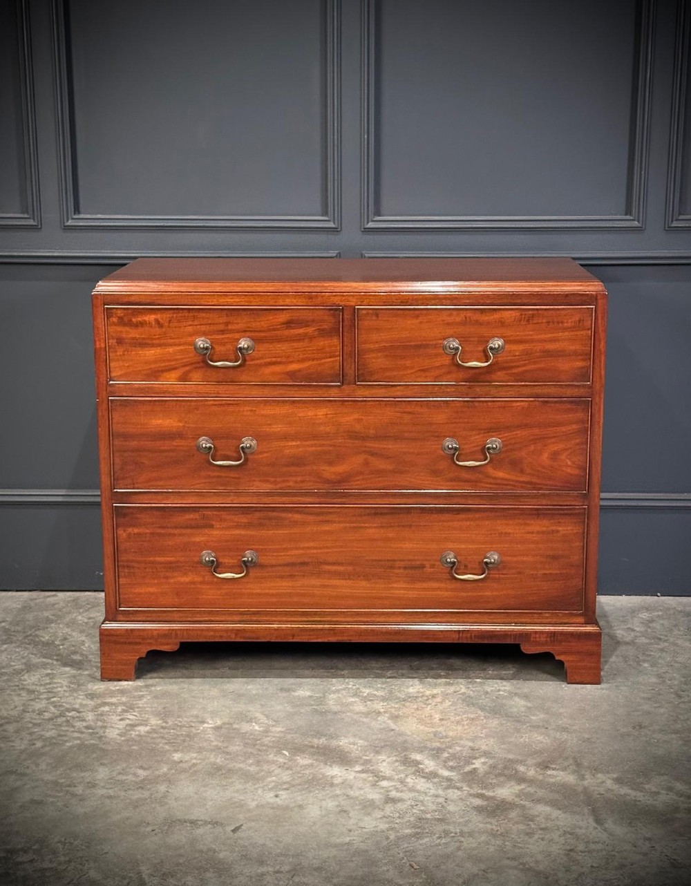 A small mahogany chest of drawers featuring two short over two long drawers with brass swan-neck handles and bracket feet. View VIII