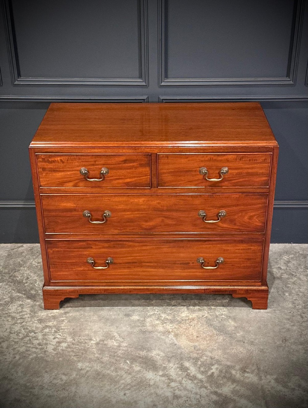 A small mahogany chest of drawers featuring two short over two long drawers with brass swan-neck handles and bracket feet. View IX