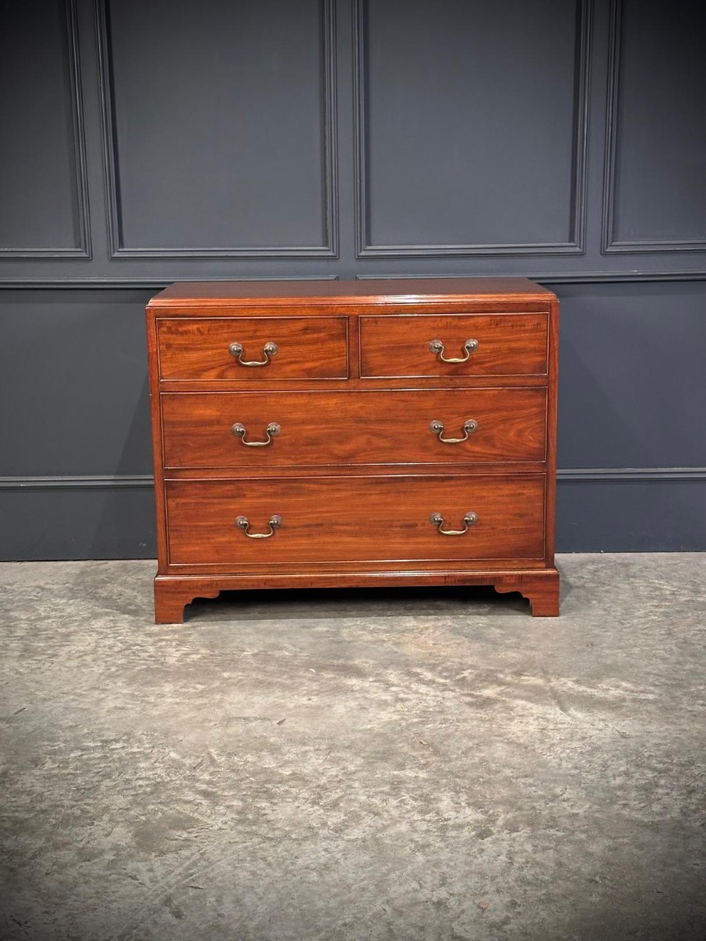A small mahogany chest of drawers featuring two short over two long drawers with brass swan-neck handles and bracket feet. View X