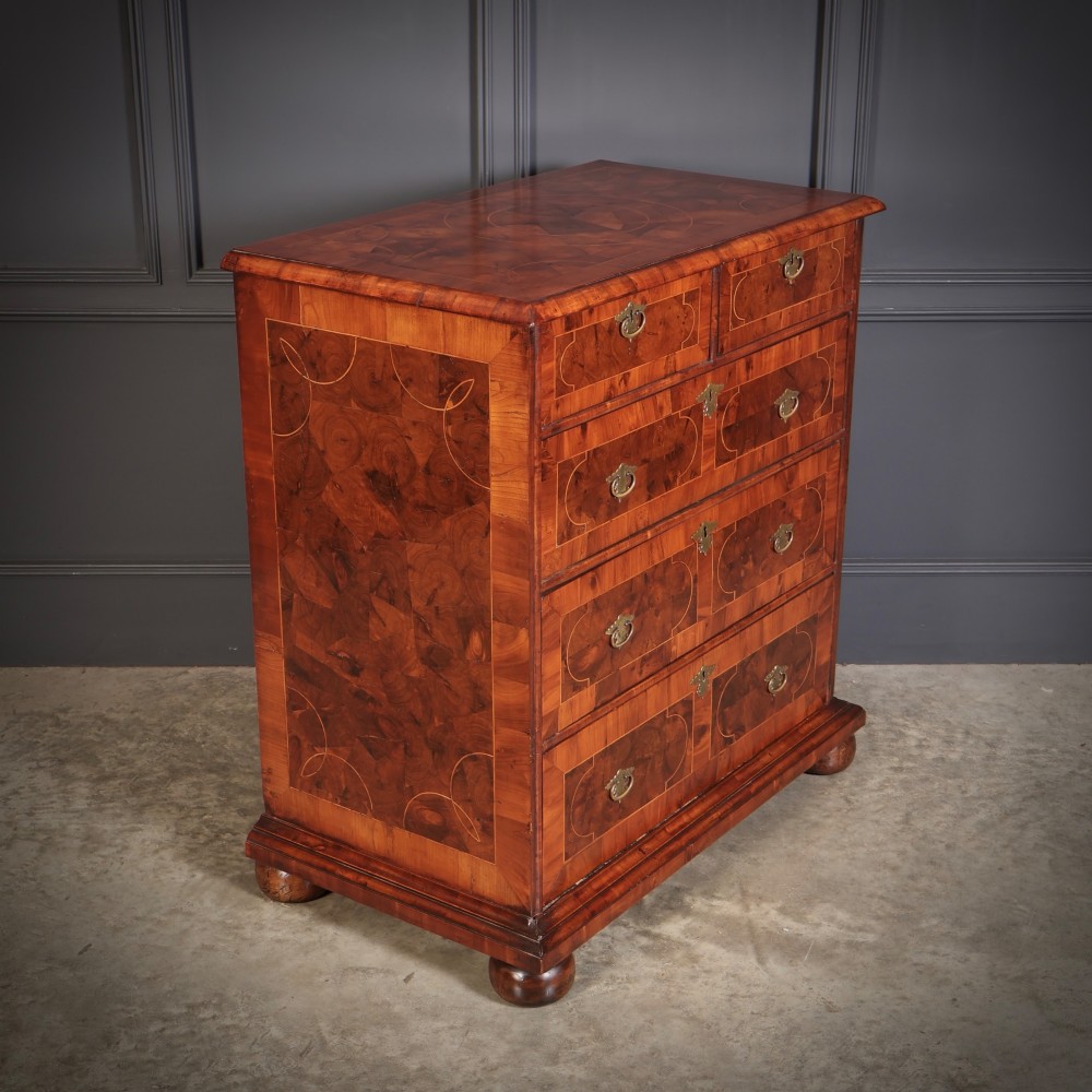 A 17th-century William and Mary chest of drawers featuring geometric oyster veneer, boxwood stringing, brass drop handles, and turned bun feet.