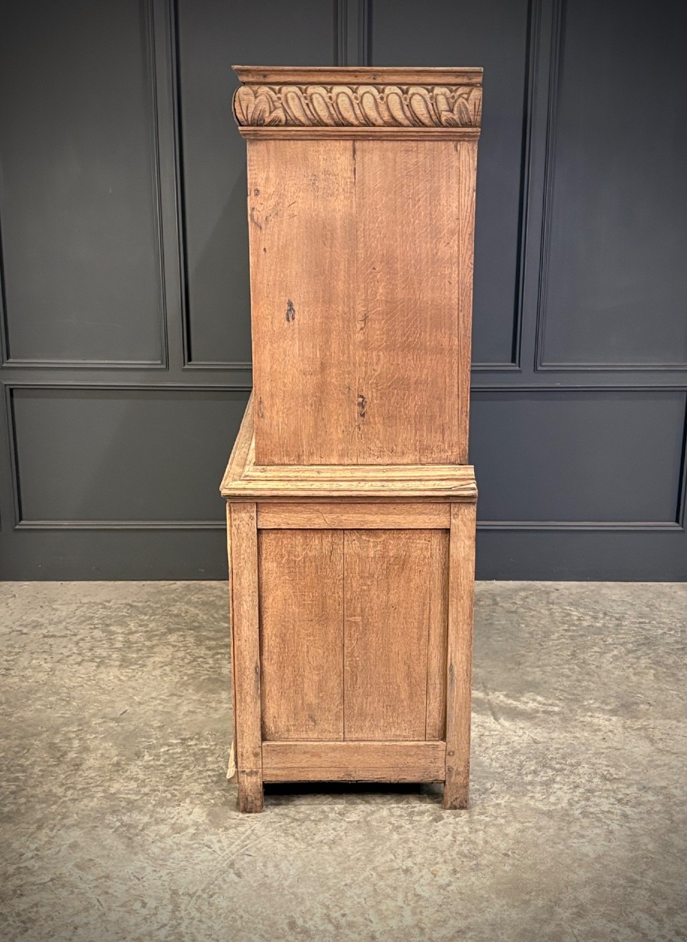 An 18th-century light oak two-piece cupboard on chest featuring detailed hand-carved foliate panels, cherub motifs, and carved drawer fronts. View IX