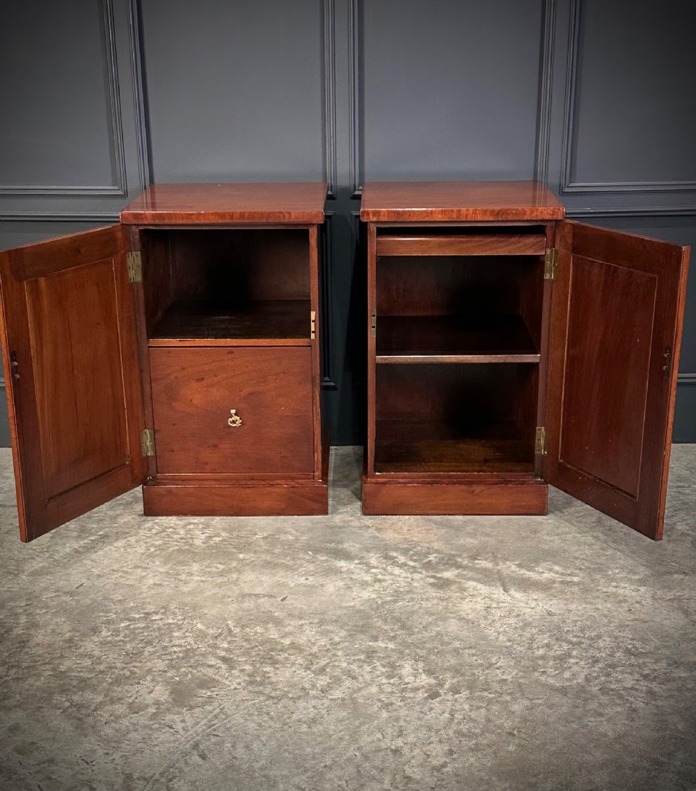 A matching pair of dark flame mahogany bedside cabinets featuring single doors with arched panels resting on solid plinth bases. View IV