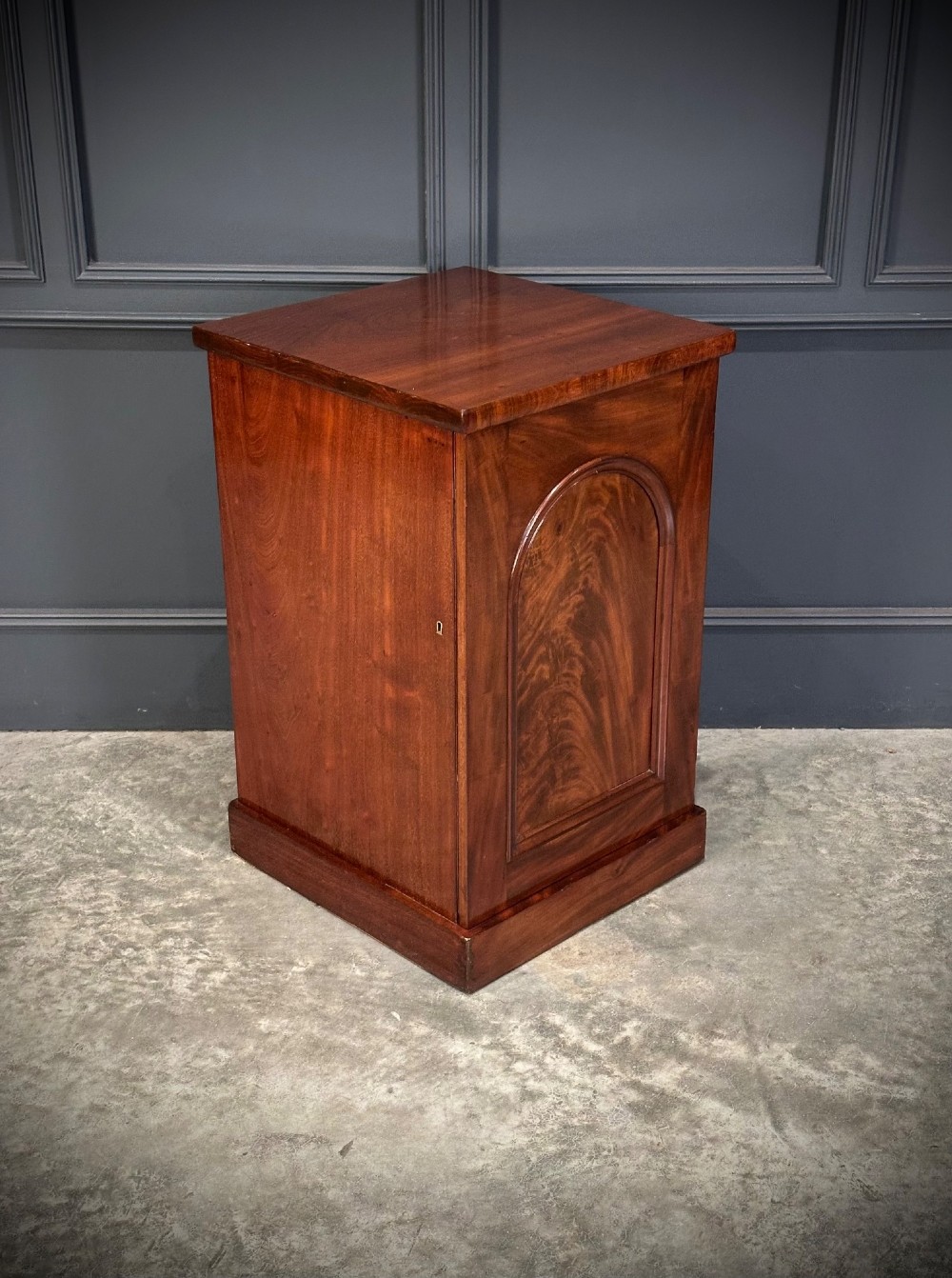 A matching pair of dark flame mahogany bedside cabinets featuring single doors with arched panels resting on solid plinth bases. View V