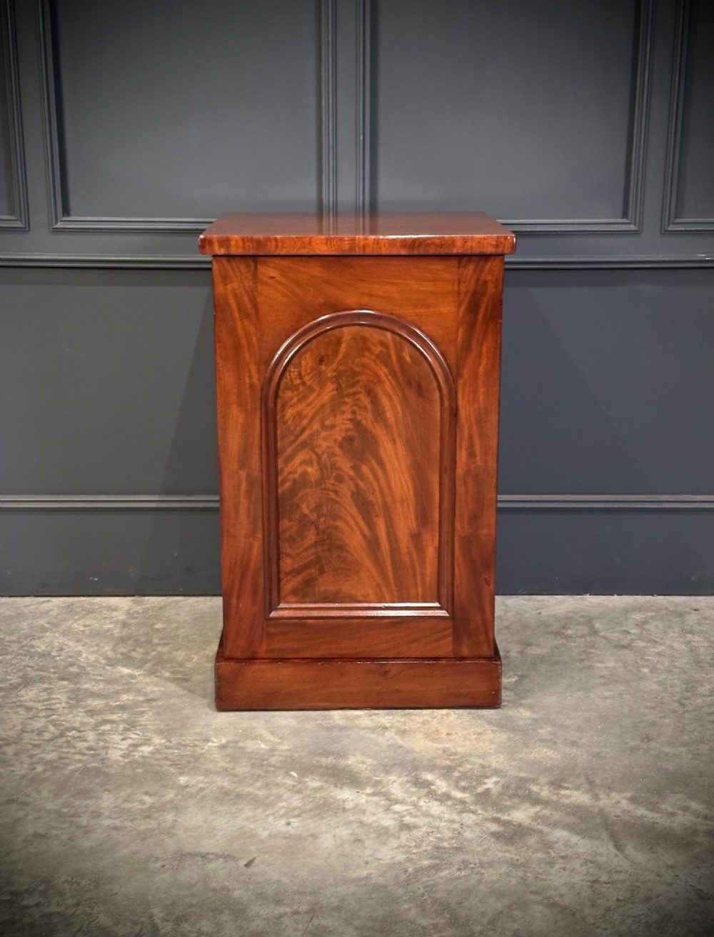 A matching pair of dark flame mahogany bedside cabinets featuring single doors with arched panels resting on solid plinth bases. View VII