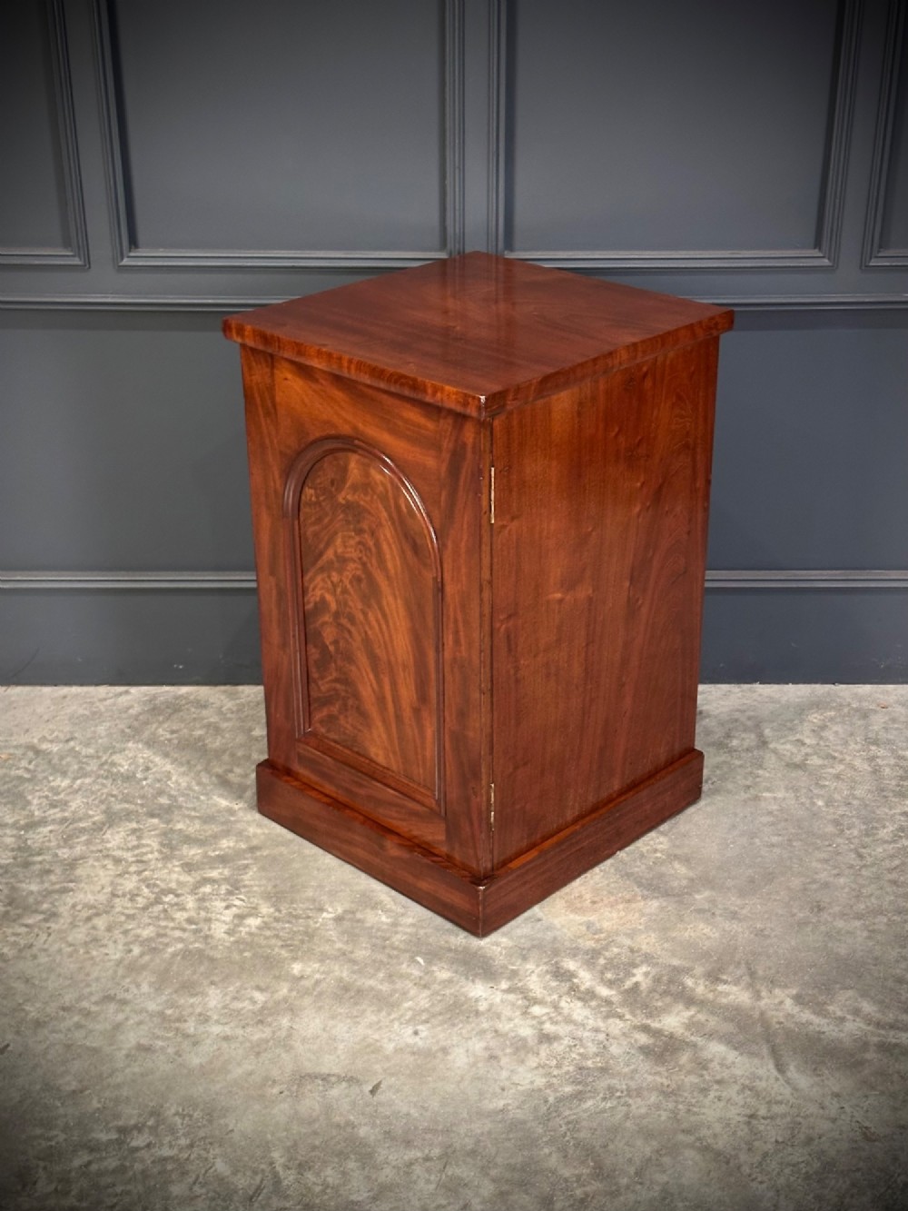 A matching pair of dark flame mahogany bedside cabinets featuring single doors with arched panels resting on solid plinth bases. View VIII