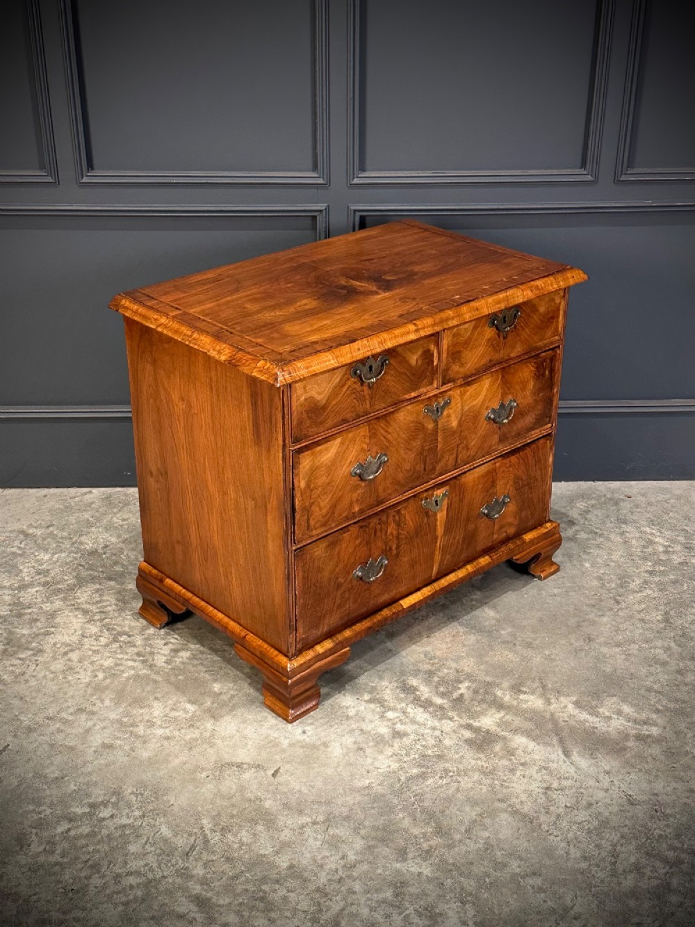 An eighteenth-century Queen Anne walnut chest of drawers featuring two short over two long graduated drawers, brass handles, and shaped bracket feet. View II