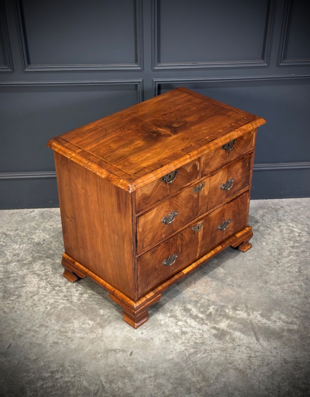An eighteenth-century Queen Anne walnut chest of drawers featuring two short over two long graduated drawers, brass handles, and shaped bracket feet. View III