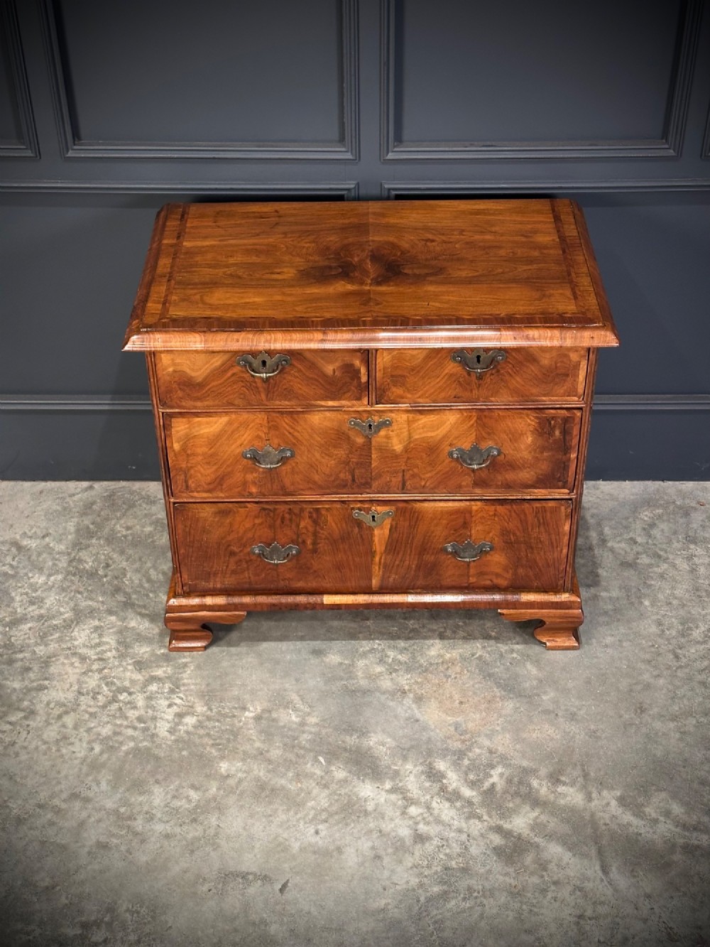 An eighteenth-century Queen Anne walnut chest of drawers featuring two short over two long graduated drawers, brass handles, and shaped bracket feet. View IV