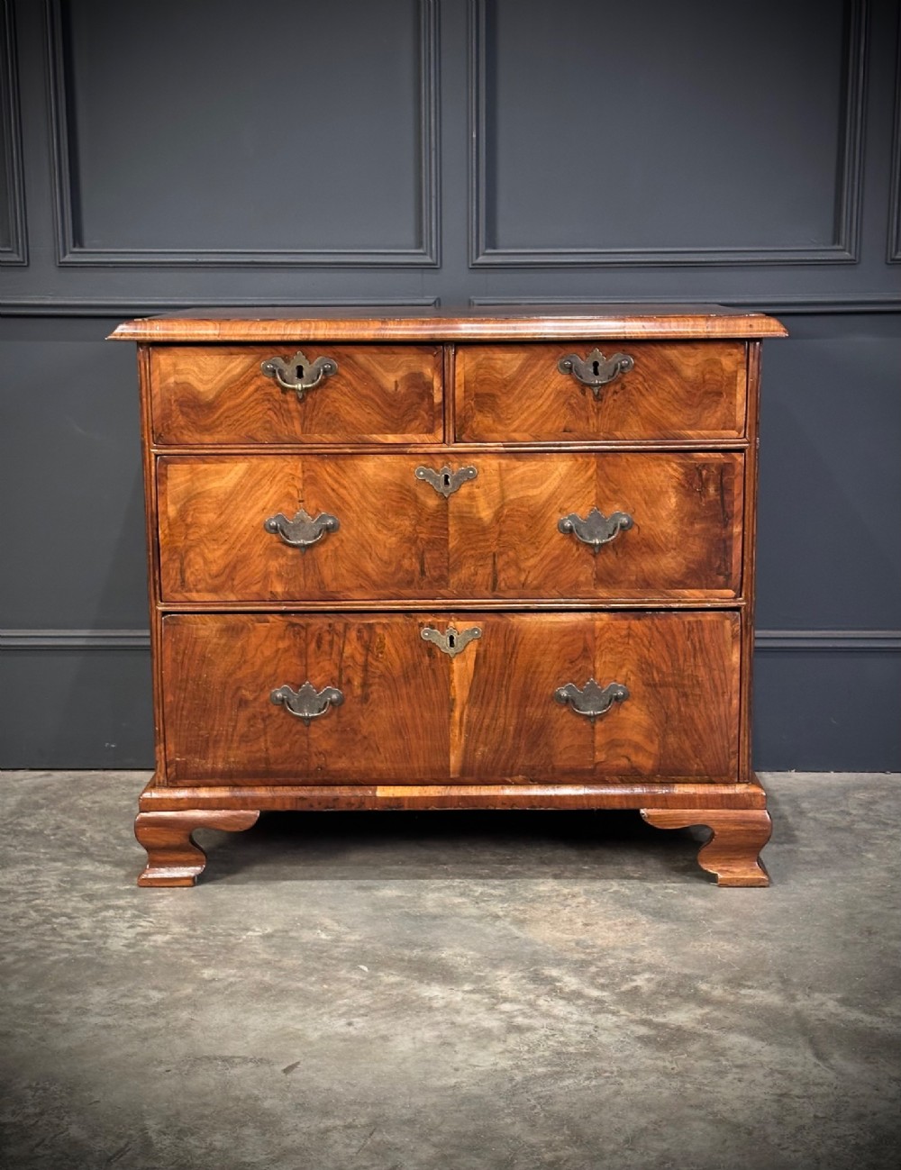 An eighteenth-century Queen Anne walnut chest of drawers featuring two short over two long graduated drawers, brass handles, and shaped bracket feet. View VI