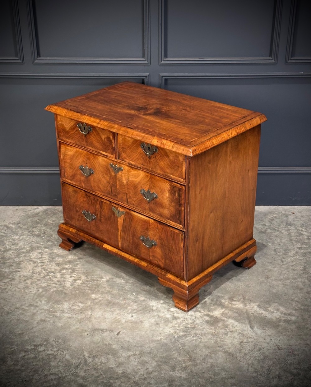 An eighteenth-century Queen Anne walnut chest of drawers featuring two short over two long graduated drawers, brass handles, and shaped bracket feet. View VII