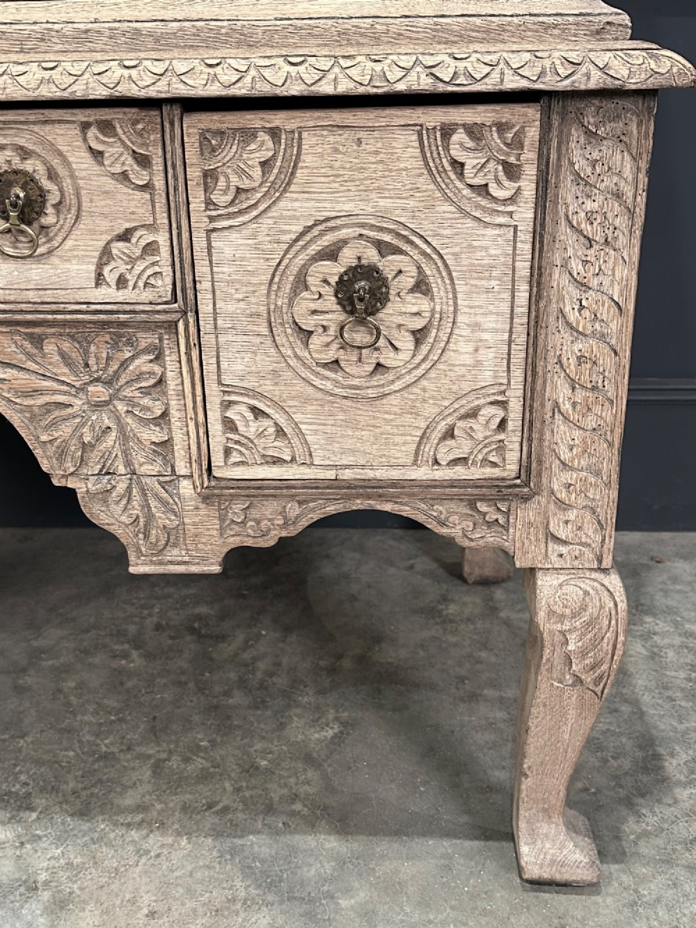 An 18th-century bleached oak chest on stand featuring carved foliage motifs across the drawer fronts and elevated on cabriole legs. View V