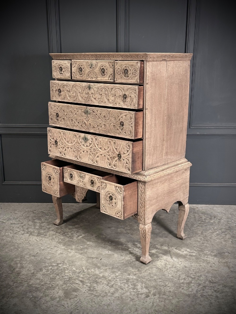 An 18th-century bleached oak chest on stand featuring carved foliage motifs across the drawer fronts and elevated on cabriole legs. View VII