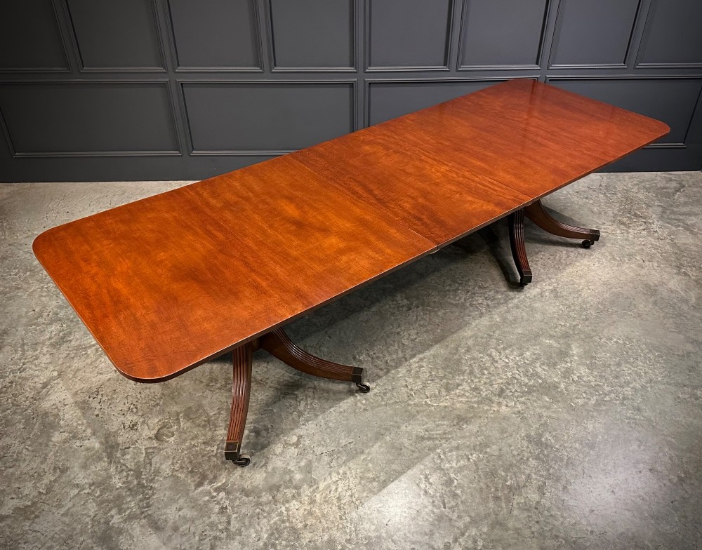 An extended mahogany twin pillar dining table with reeded splayed legs and brass castors. View II