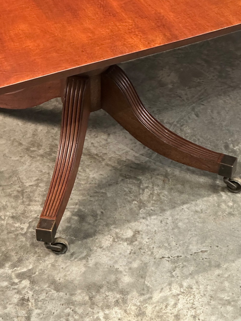 An extended mahogany twin pillar dining table with reeded splayed legs and brass castors. View III