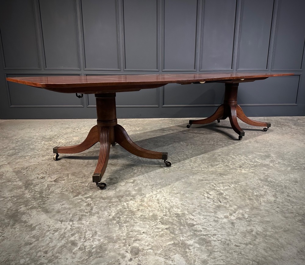 An extended mahogany twin pillar dining table with reeded splayed legs and brass castors. View IV