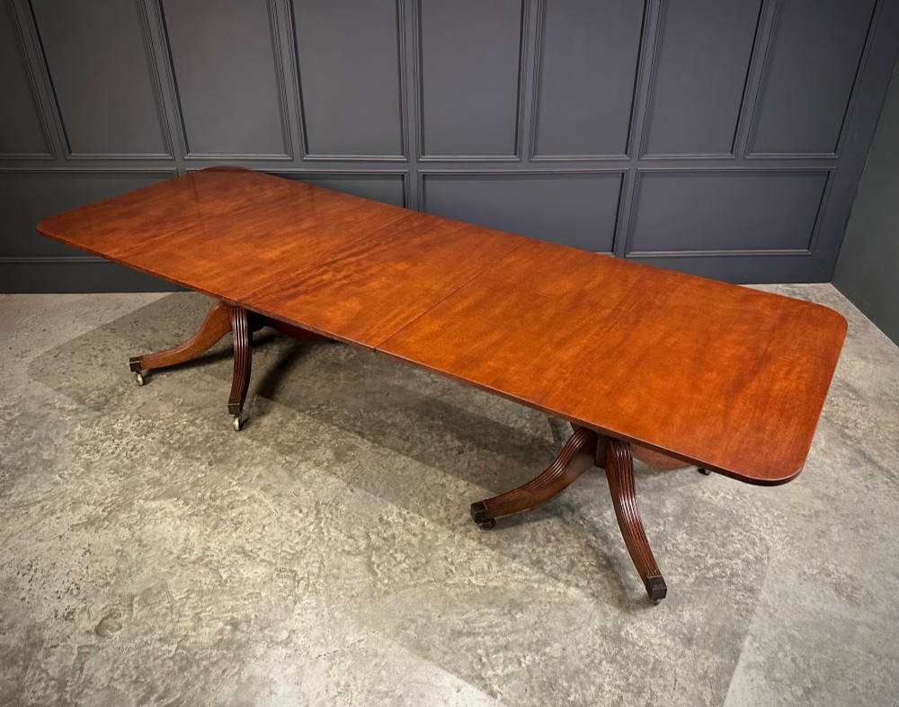 An extended mahogany twin pillar dining table with reeded splayed legs and brass castors. View VI
