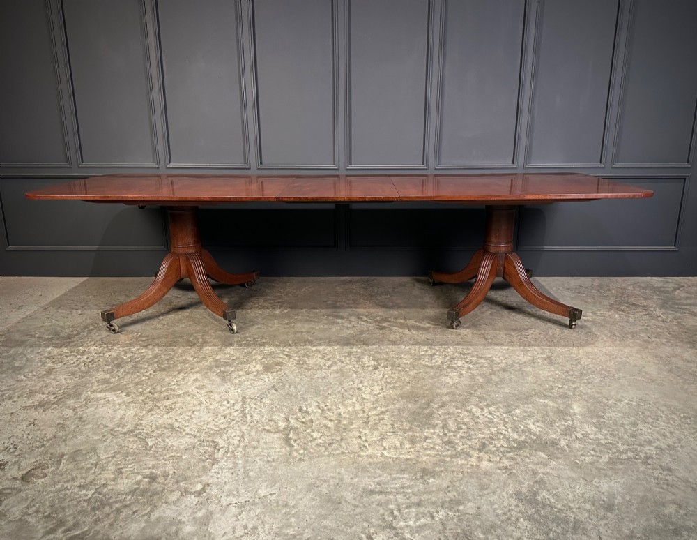 An extended mahogany twin pillar dining table with reeded splayed legs and brass castors. View VII