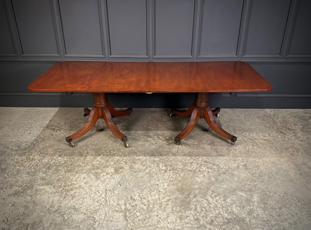 An extended mahogany twin pillar dining table with reeded splayed legs and brass castors. View VIII