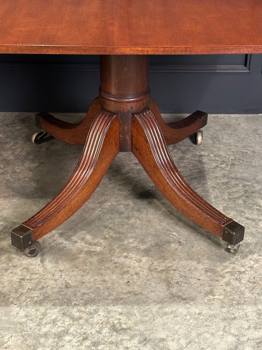 An extended mahogany twin pillar dining table with reeded splayed legs and brass castors. View IX