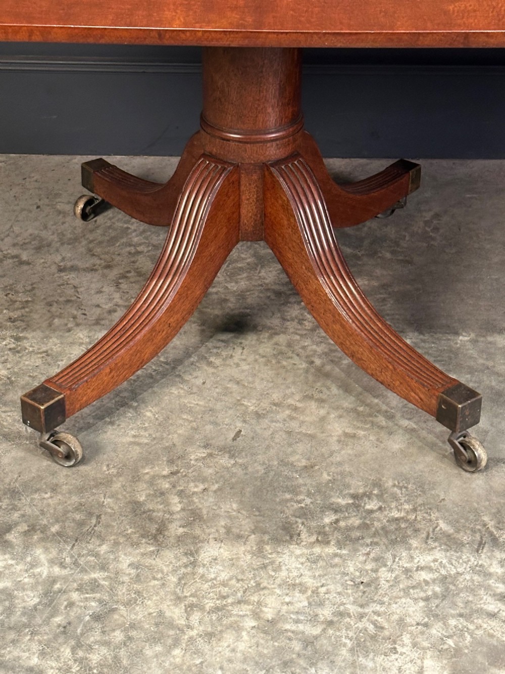 An extended mahogany twin pillar dining table with reeded splayed legs and brass castors. View X