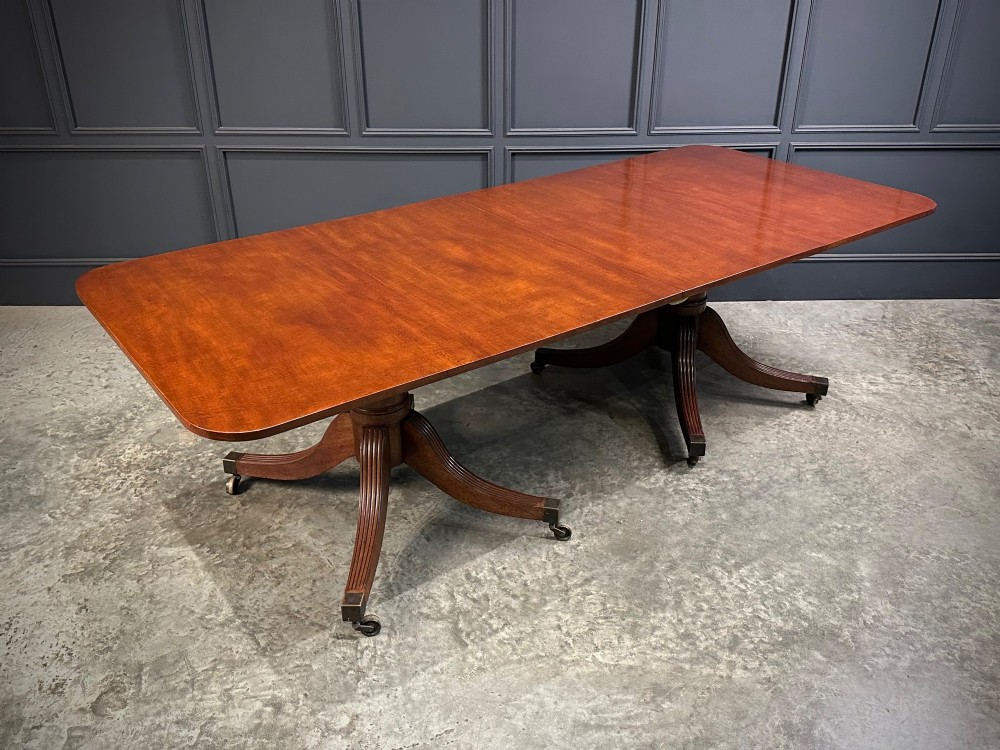 An extended mahogany twin pillar dining table with reeded splayed legs and brass castors. View XI