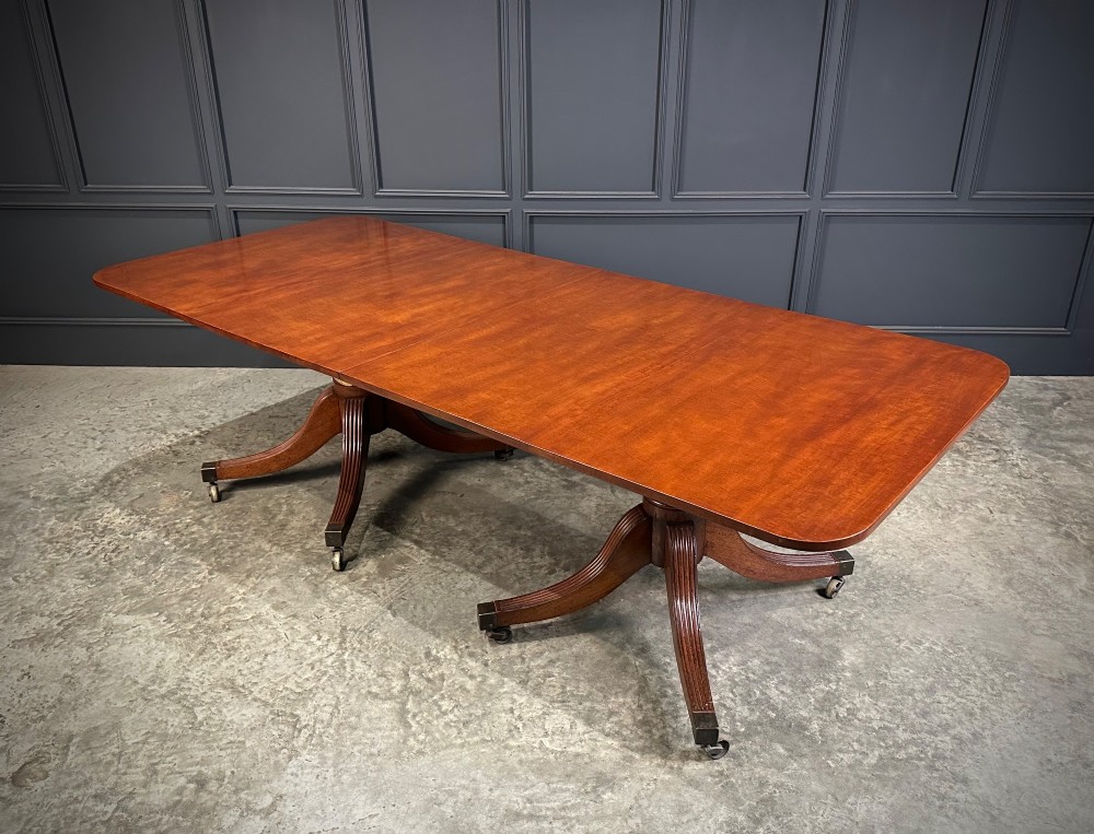 An extended mahogany twin pillar dining table with reeded splayed legs and brass castors. View XII